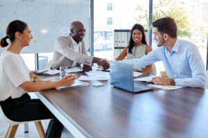 Four salespeople sitting around table onboarding new hire