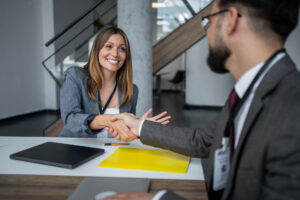 Two businesspeople shaking hands in a modern office, expressing joy and satisfaction after successfully finalizing their agreement during a productive meeting