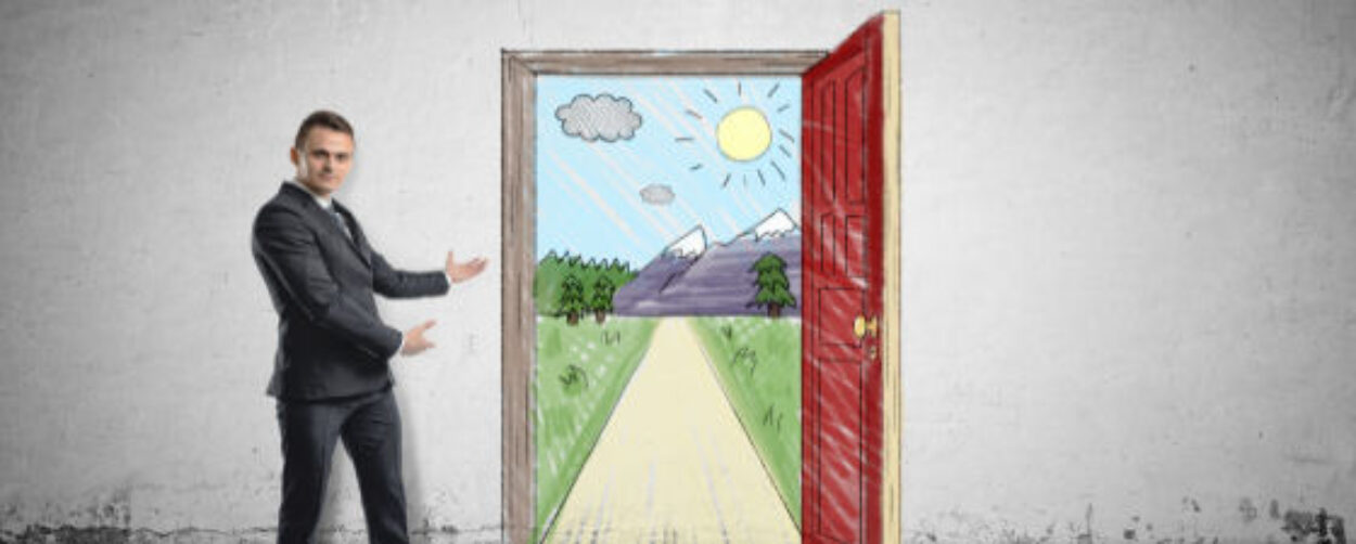 Businessman stands showing sunny scene with the road and mountains behind an open door by both hands. Unlimited possibilities. Opportunities and advantages.